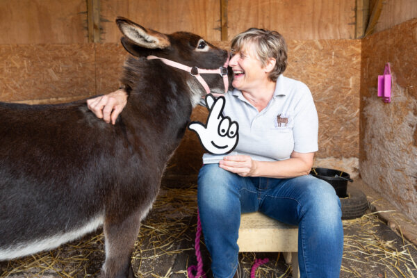 A woman (Sarah McPherson) holding a National Lottery Award trophie with her miniature donkey